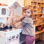 Lille pige laver mad på legetøjskøkken