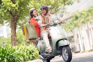 Midaldrende par på scooter med indkøbsposer